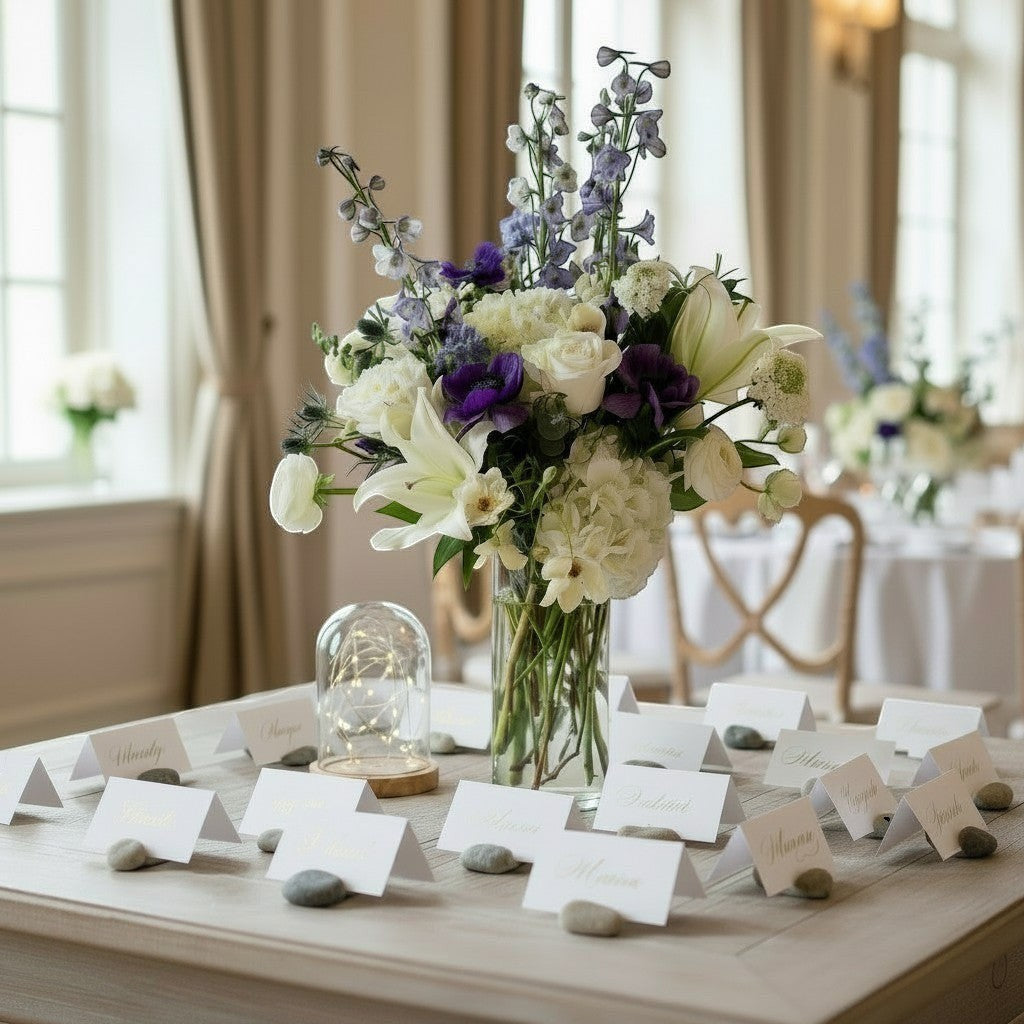 Town & Country Gardens Inc floral arrangement with blue delphinium, white hydrangeas, and roses in a glass vase.